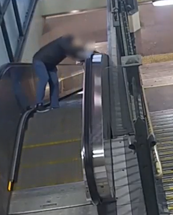 A person loses their footing on a station escalator. 